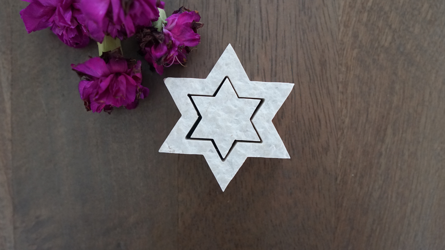 Two piece Star of David made from Jerusalem stone on table with flowers